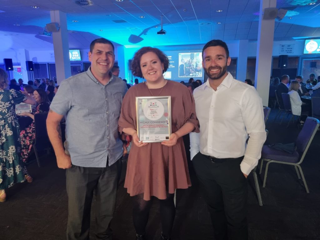 Three staff members holding an award